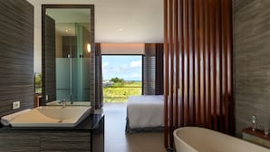 A modern hotel room with a large bed, a bathroom with a bathtub, a sink, and a large window offering a view of the outdoors. - Best Seller 2 Bedrooms Villa in Central Seminyak (Seminyak)