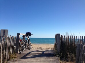 A wooden pathway leading to a beach with a bicycle parked on the left.