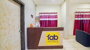 A reception desk with a 'fab hotels' sign, a door, and red curtains. - Fabexpress Srinivasan Apartment (Vandavasi)