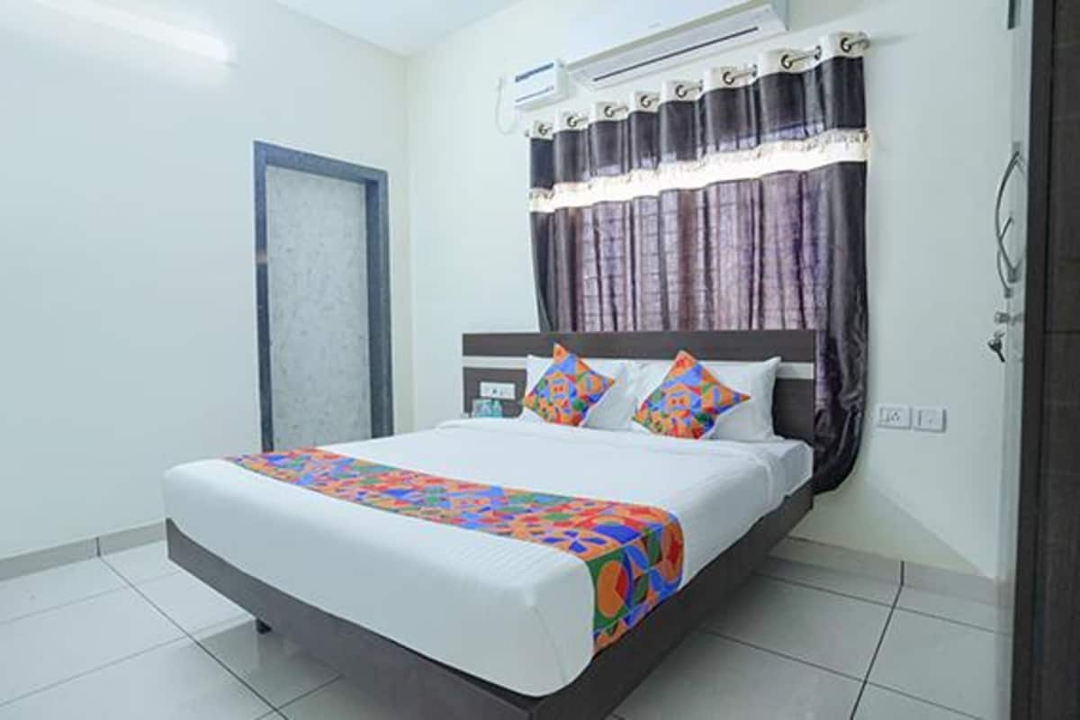 Une chambre d’hôtel avec un grand lit, une fenêtre avec des rideaux, un appareil de climatisation et un sol carrelé.