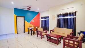 A living room with a sofa, chairs, a coffee table, and a ceiling fan. - Fabexpress Srinivasan Apartment (Vandavasi)