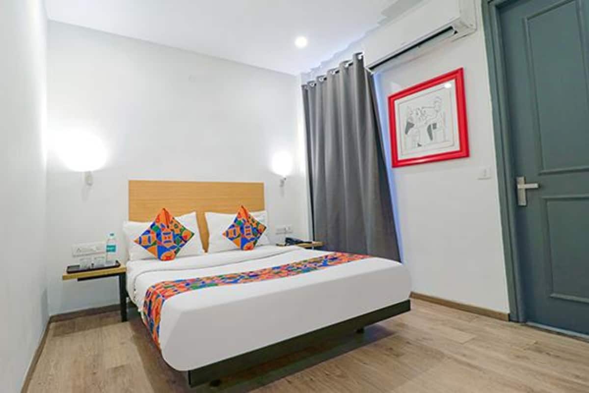Une chambre d’hôtel avec un lit, une table de chevet, une bouteille d’eau et un tableau encadré au mur.