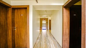 A hotel corridor with wooden doors numbered 205 and 202, leading to an elevator. - Fabhotel Happy Stay (Pune)