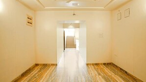 A hotel hallway with a marble floor, a ceiling fan, and a staircase leading to another floor. - Fabhotel Happy Stay (Pune)