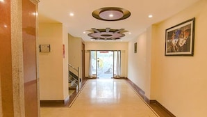 Un pasillo de hotel con piso pulido, techo con iluminación empotrada y una obra de arte enmarcada en la pared.