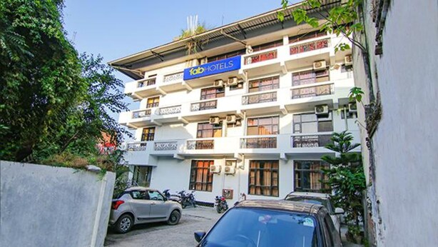 Un edificio de varios pisos con un letrero de 'fab hotels', con balcones y unidades de aire acondicionado.