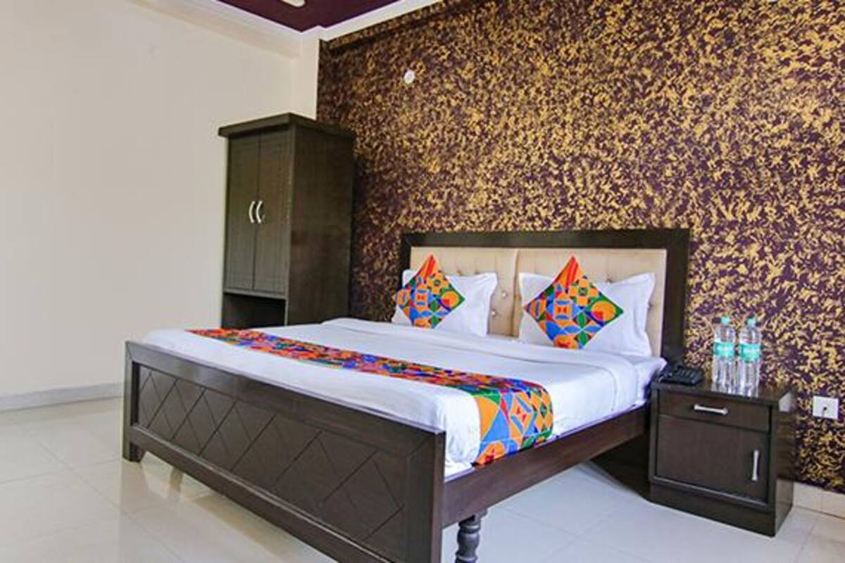 Une chambre à coucher avec un lit, une table de chevet, une armoire et un mur décoré d’un motif.