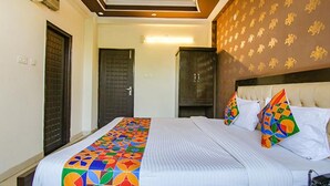 Una habitación de hotel con una cama, cabecero y un papel tapiz estampado.