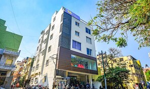 Un edificio de varios pisos con fachada moderna, un letrero visible de 'Fab Hotels' y una entrada a nivel de calle con ventana de vidrio.