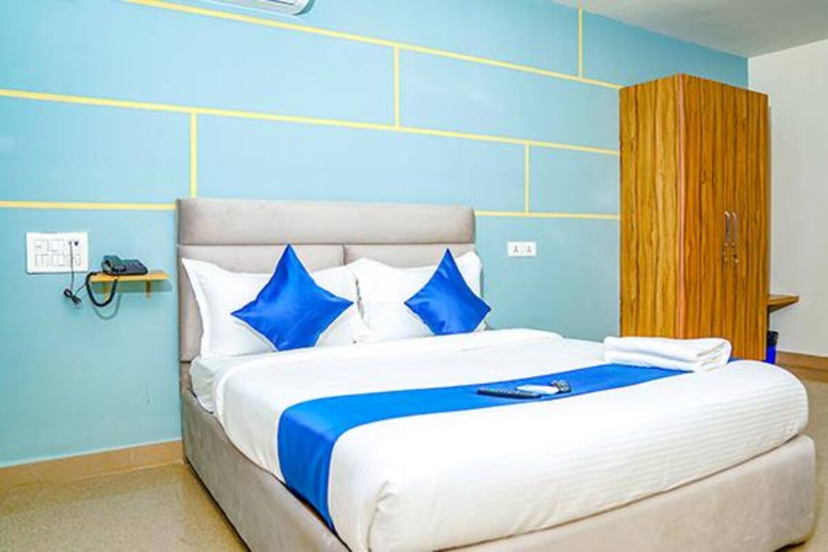 Quarto com cama, almofadas azuis, mesa de cabeceira e guarda-roupa de madeira.