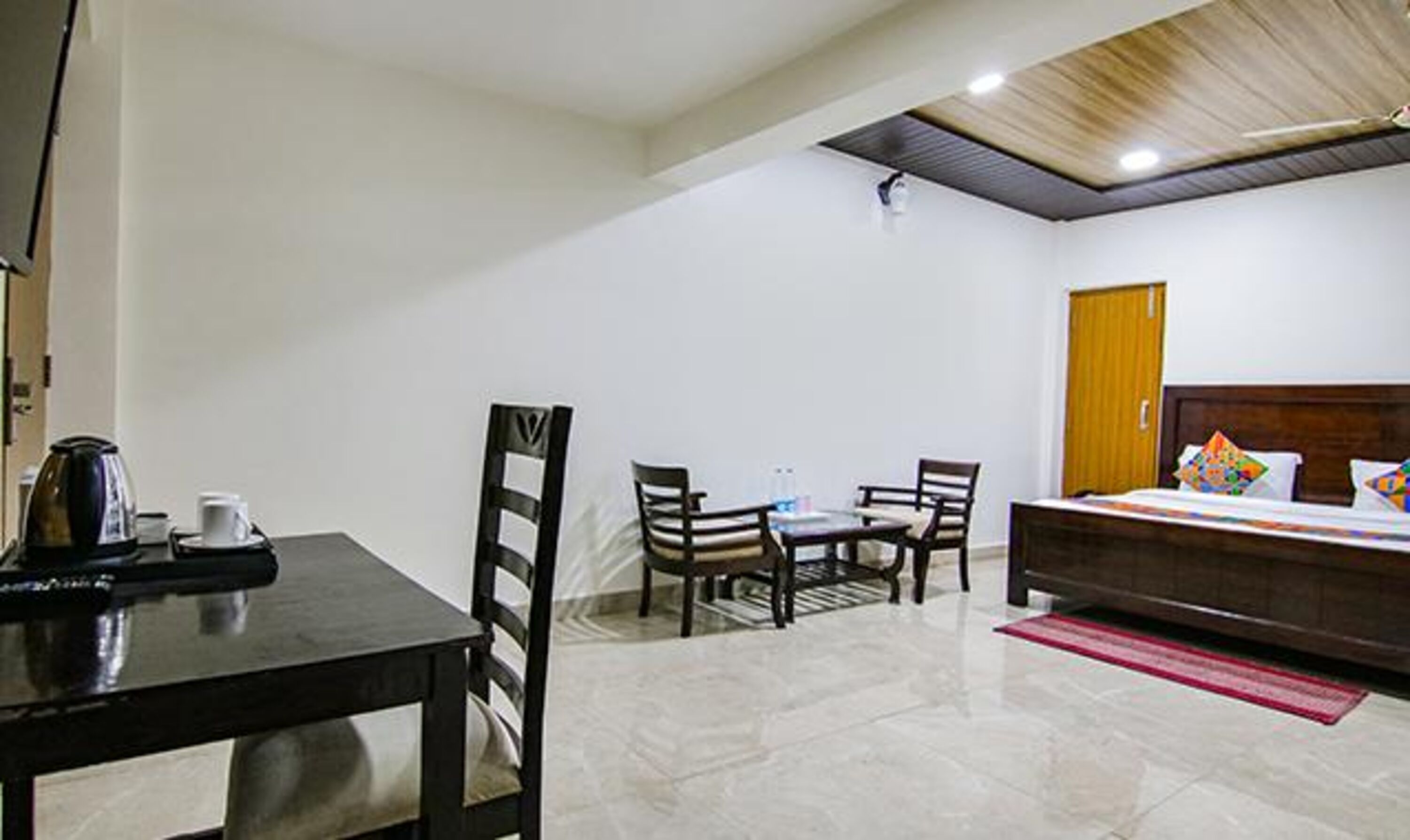 A hotel room with a bed, a desk, and a chair. There is a coffee maker on the desk.