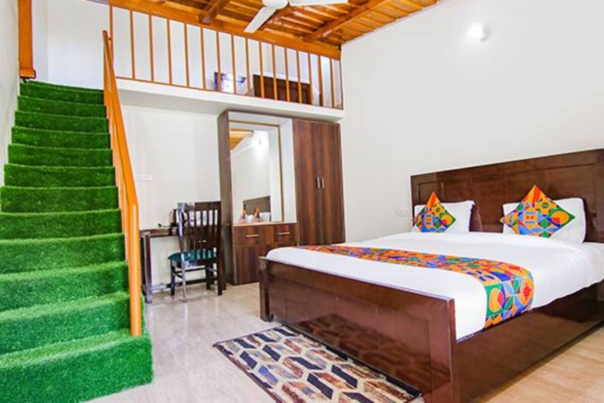 Ein Schlafzimmer mit Bett, Schreibtisch, Stuhl, Kleiderschrank und einer Treppe mit Grastritten.