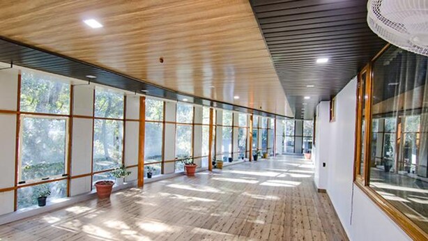 A long corridor with wooden floors and large windows, allowing natural light to enter. - Fabhotel Wildflower Inn (Nainital)