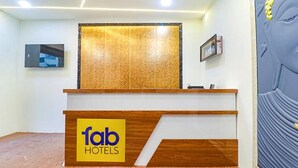 A reception desk with a wooden finish and a 'fab hotels' logo. - Fabhotel Elite Inn (Bengaluru)