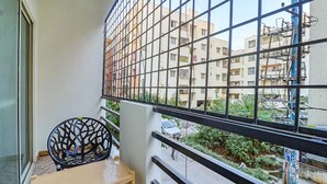 A balcony with a view of a residential area, a chair, and a small table. - Fabhotel Elite Inn (Bengaluru)
