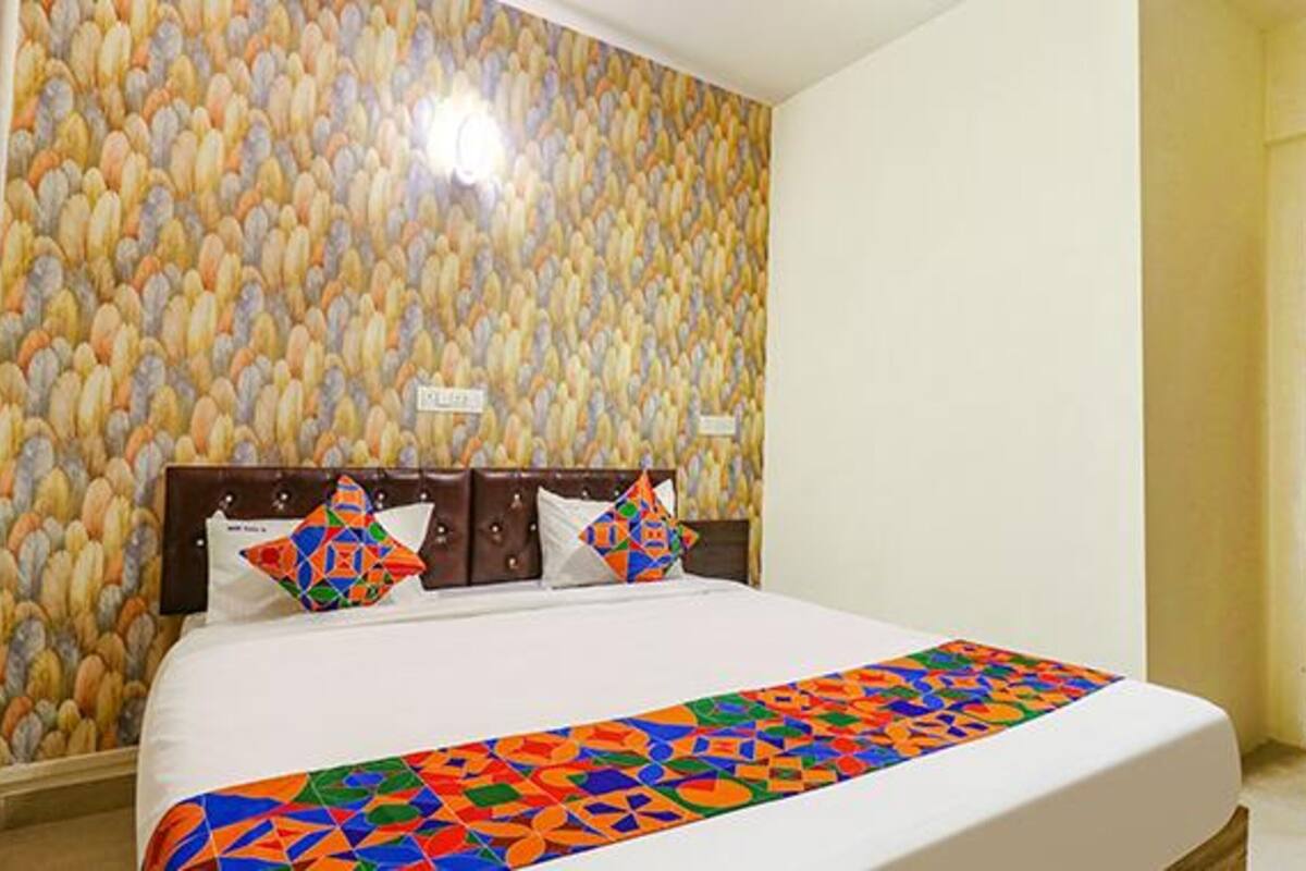 A hotel room with a bed, pillows, and a patterned wall.