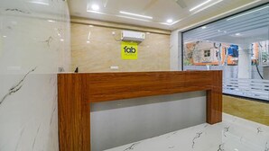 A hotel reception desk with a wooden finish, a marble floor, and a large window offering a view of the outside. - Fabhotel Stone Gallery (Hyderabad)