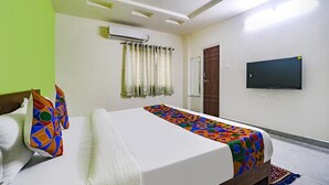 A hotel room with a bed, a TV mounted on the wall, and a door. - Fabhotel Stone Gallery (Hyderabad)