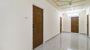 A hallway with wooden doors, a ceiling fan, and a marble floor. - Fabhotel Stone Gallery (Hyderabad)