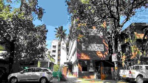 Una vista de carrer amb cotxes aparcats, edificis i arbres.
