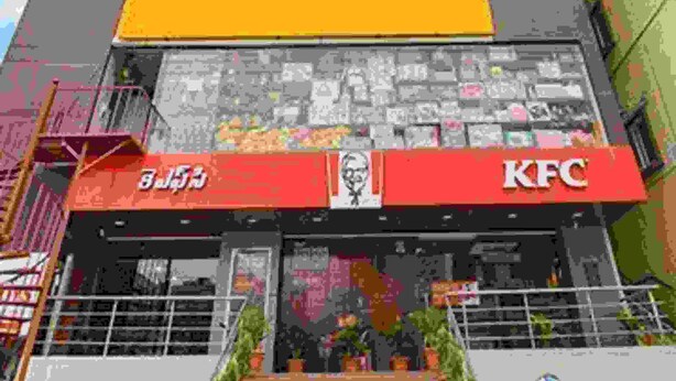 A multi-story building with a prominent 'fabHOTELS' sign on the second floor, a 'JPS Plaza' sign on the first floor, and 'KFC' and 'BJ's' signs on the ground floor. - Fabexpress Star Kinghood Inn (Hyderabad)