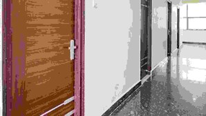 A hallway with a wooden door on the left and a door on the right. - Fabexpress Star Kinghood Inn (Hyderabad)