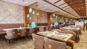 A restaurant with booths and tables, wooden paneling, and hanging pendant lights. - Fabhotel Twin Tree Suites (Hyderabad)