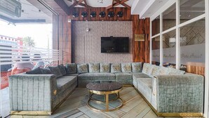 A modern living room with a sectional sofa, a round coffee table, and a flat-screen TV mounted on the wall. - Fabhotel Twin Tree Suites (Hyderabad)