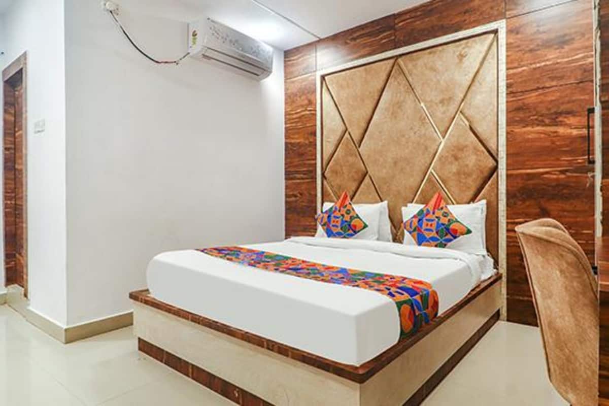 Quarto com cabeceira de madeira, cama com almofadas coloridas e uma cadeira.