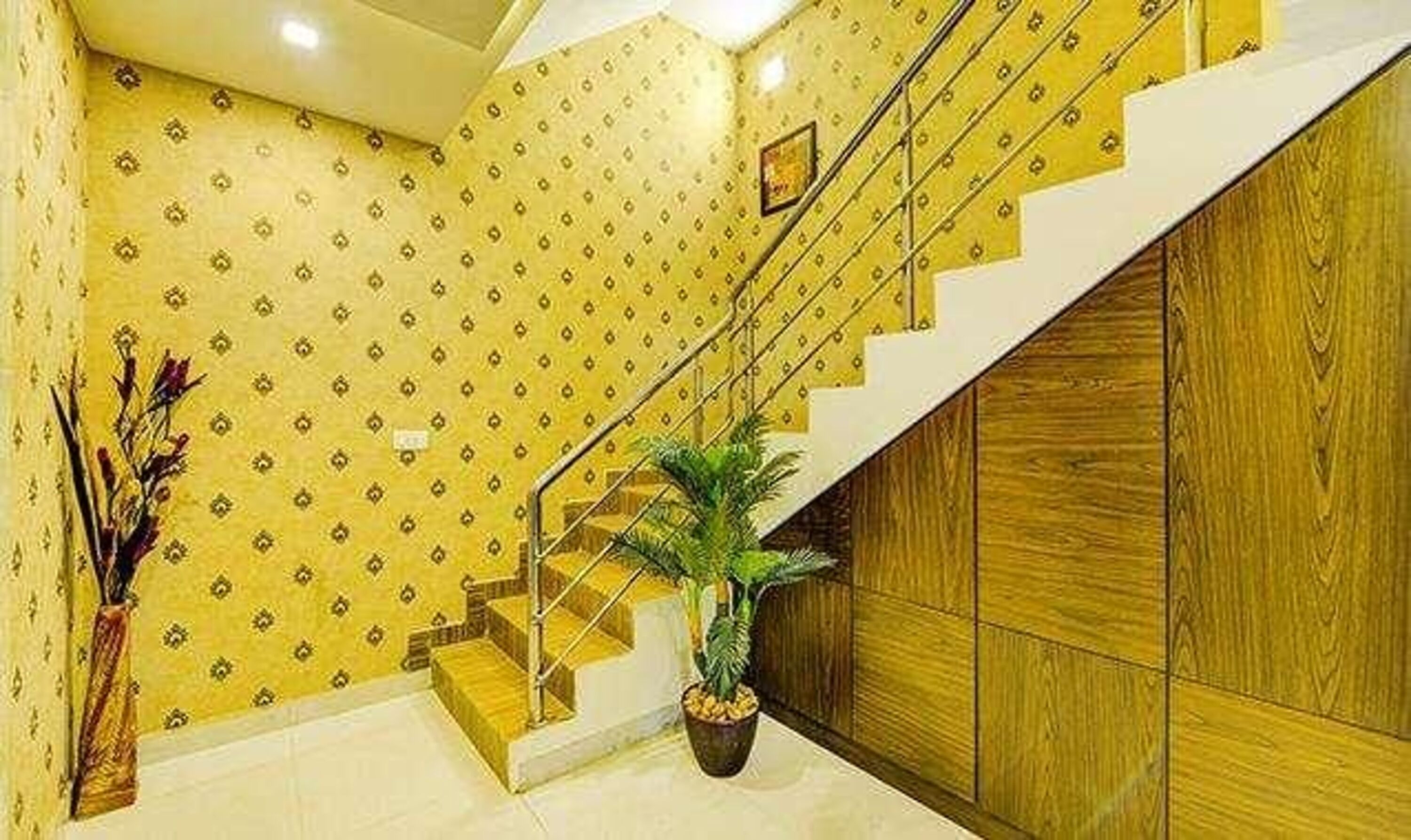 Un escalier avec une rampe en bois et un pot de fleurs à sa base.