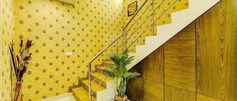 Un escalier avec une rampe en bois et un pot de fleurs à sa base.