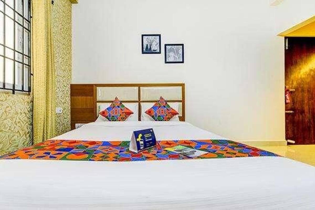 A hotel room with a large bed, a wooden headboard, and two framed pictures on the wall.