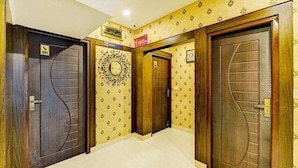 A hallway with three wooden doors, each with a unique design. - Fabhotel Ruchikkoot Bay (Chennai)
