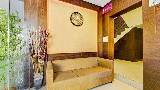 A reception area with a sofa, a decorative wall plate, and a staircase. - Fabhotel Ruchikkoot Bay (Chennai)