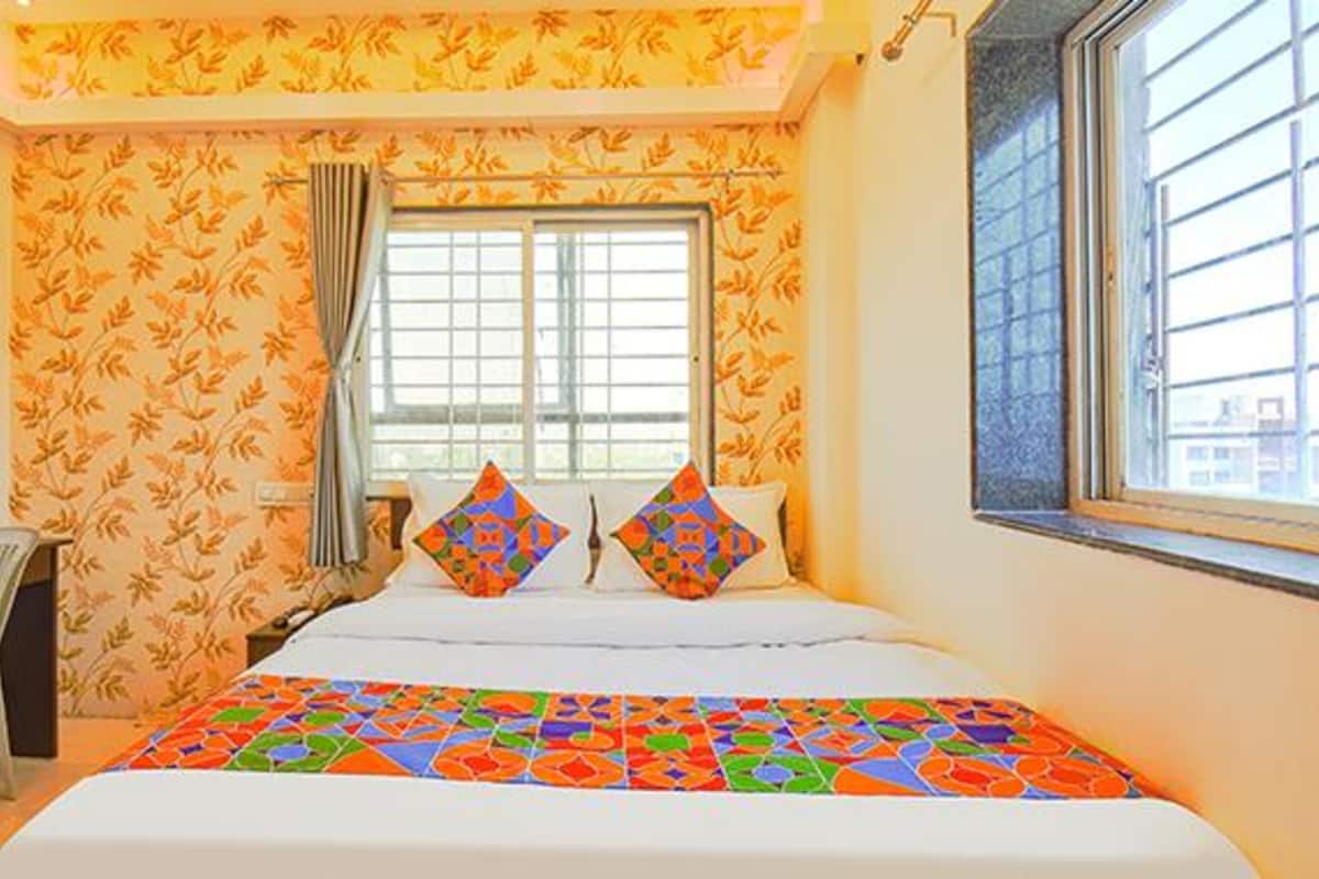 A hotel room with a bed, a desk, and a window.