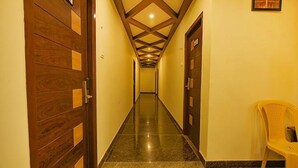 Un pasillo con puertas de madera, una pared amarilla y una silla de plástico.