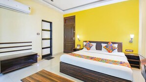 A hotel room with a bed, bedside tables, a bench, and a door. - Fabhotel Envirosafe Stays (Pune)