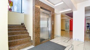 A modern elevator with a granite wall, a carpeted entrance, and a marble floor. - Fabhotel Envirosafe Stays (Pune)
