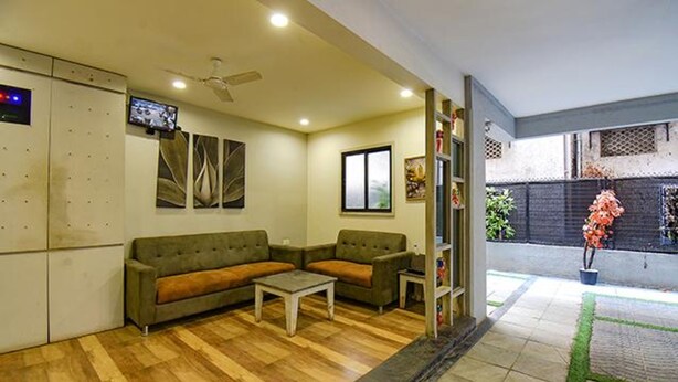 A living room with a sofa, a coffee table, and a TV. - Fabhotel Rs Apartment (Pune)