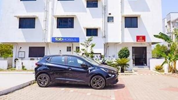 A modern building with a car parked in front. It has multiple windows and a sign that says "TOBY'S". - Fabexpress Svs Residency (Chennai)