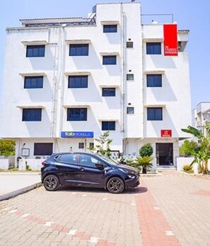 A modern building with a car parked in front. It has multiple windows and a sign that says "TOBY'S". - Fabexpress Svs Residency (Chennai)