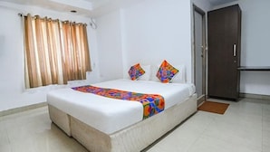 A hotel room with a large bed, a window with curtains, a door, and a tiled floor. - Fabexpress Svs Residency (Chennai)