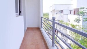 A narrow balcony with a tiled floor and a metal railing. - Fabexpress Svs Residency (Chennai)