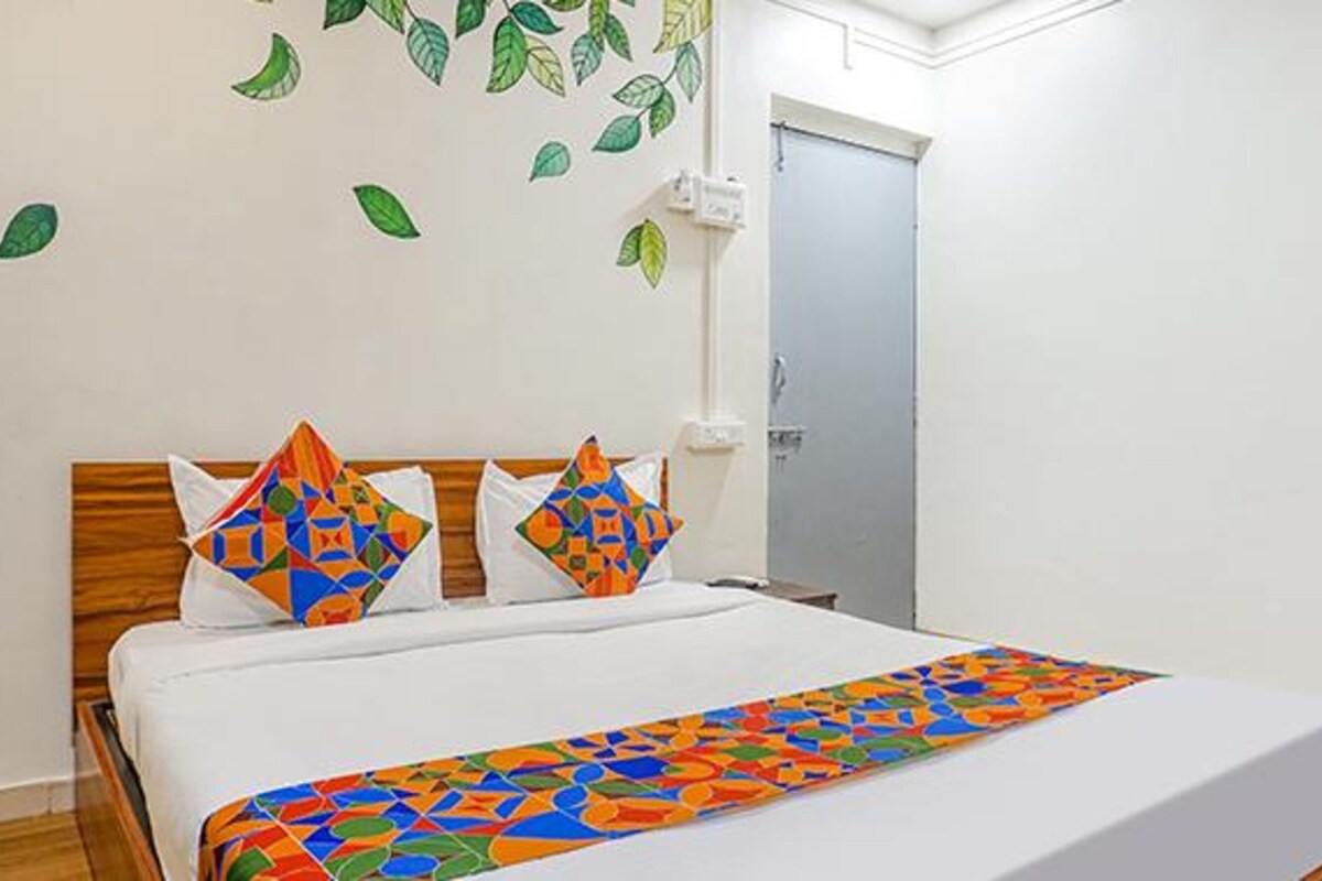A hotel room with a bed, a door, and a wall with leaf decals.