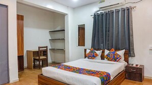 A bedroom with a bed, a desk, and a chair. - Fabhotel Aursai (Pune)