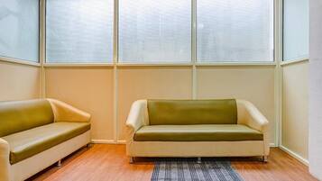 A room with two sofas, a patterned rug, and large windows.