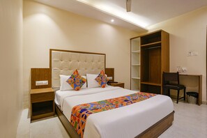 A neatly arranged bedroom with a large bed, a wooden nightstand, a desk, and a wardrobe. - Via Wynd (Mumbai)