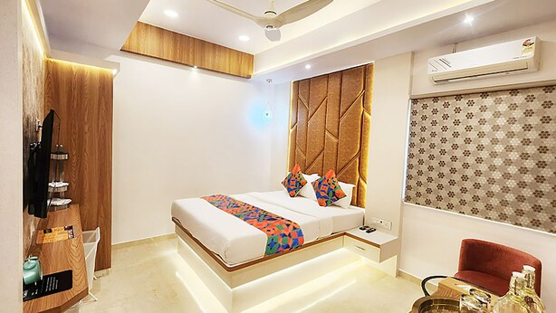 A modern bedroom with a bed, bedside table, and a red chair. - Via Wynd (Mumbai)