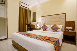 A hotel room with a large bed, a bedside table with a lamp, a chair, and a wardrobe. - Via Wynd (Mumbai)