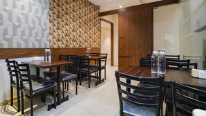 A modern dining area with wooden tables and chairs, geometric patterned walls, and a wooden partition. - Via Wynd (Mumbai)